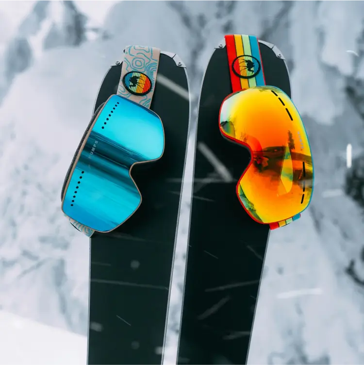 Brightly coloured ski googles resting on a pair of skis.